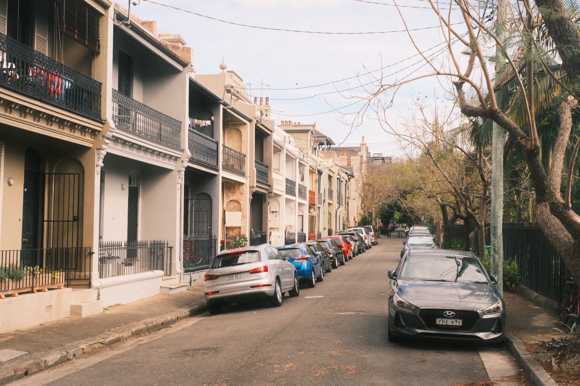 Terraces step down a slope; cars are parked tight along one side of the street.