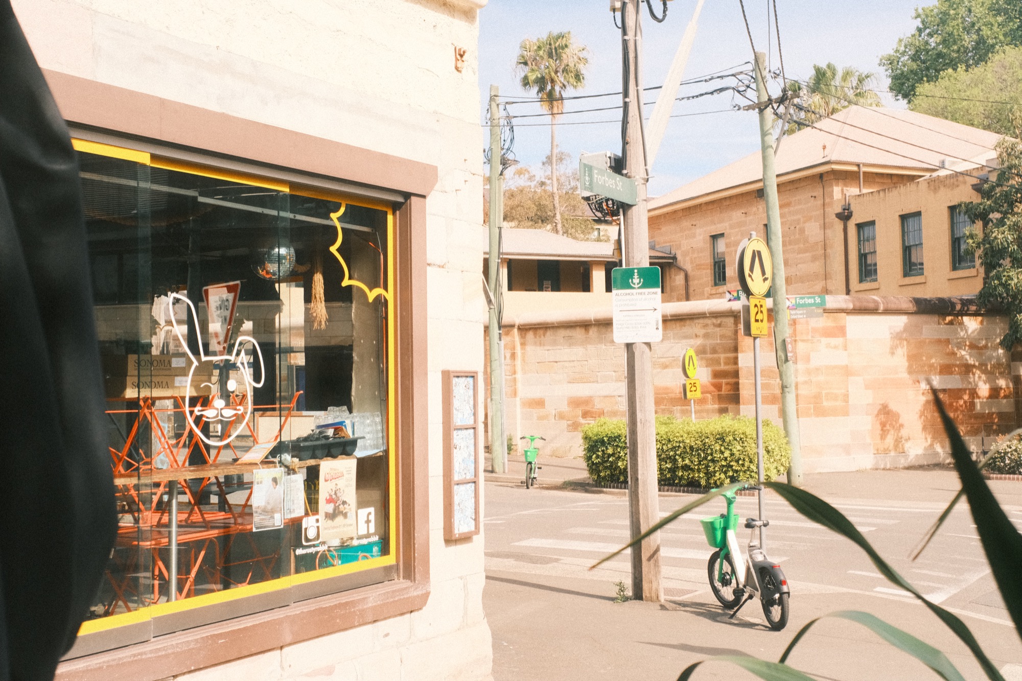 The Rusty Rabbit, a corner café: orange chairs stand stacked behind the window, a rabbit logo on the glass.
