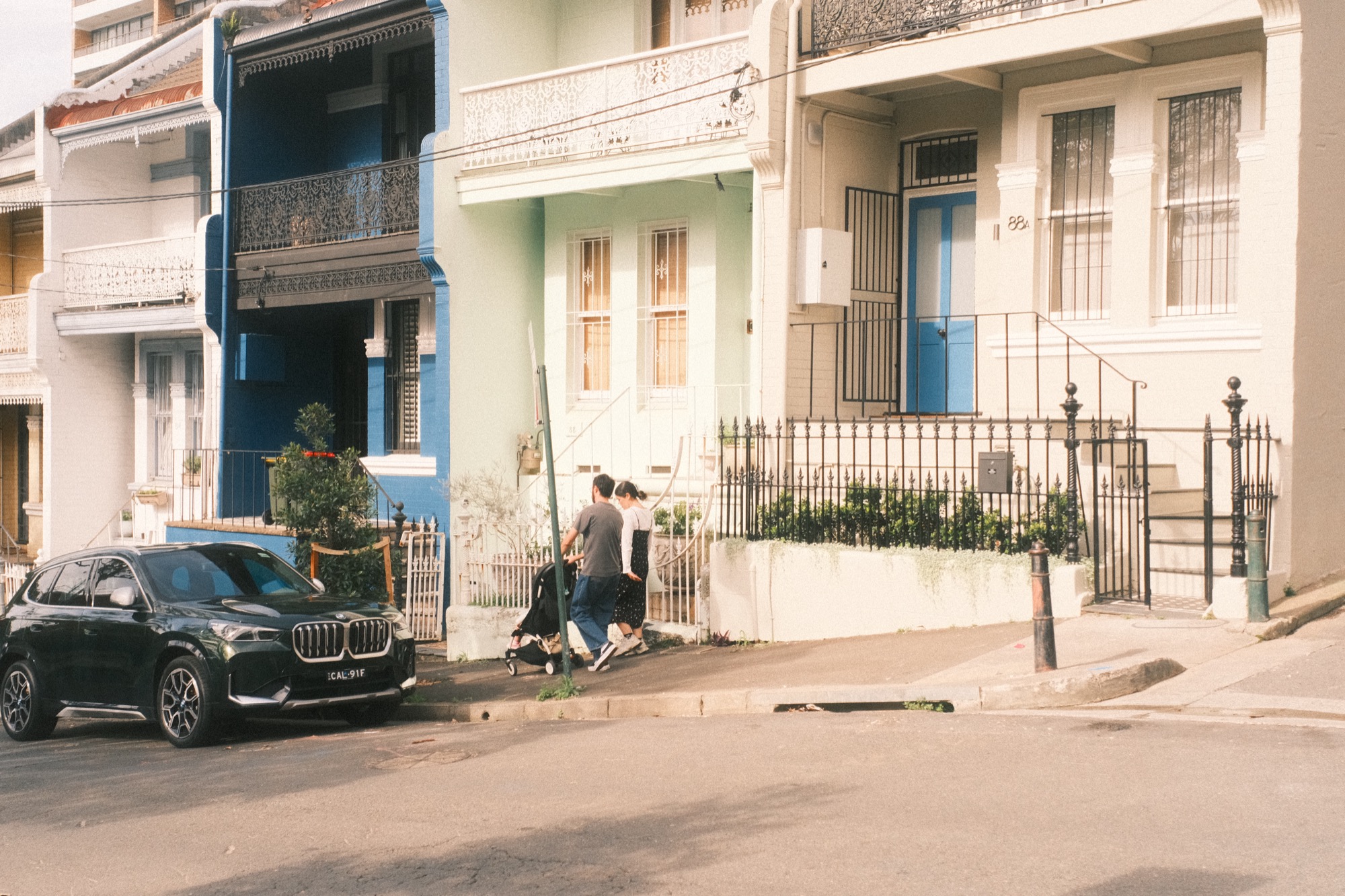 A family walks down the pavement in the evening sun.