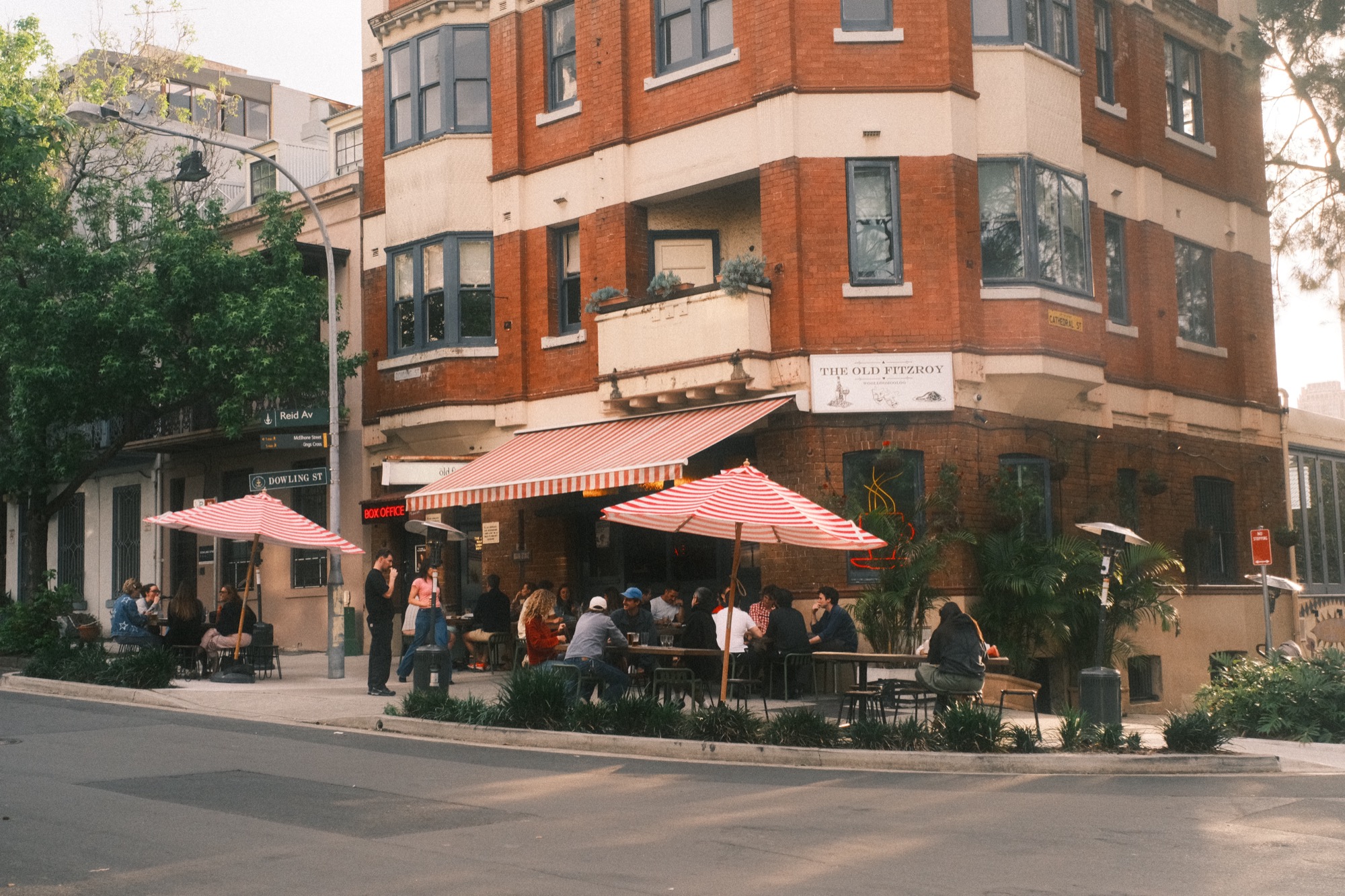 The Old Fitzroy Hotel: striped umbrellas over the pavement tables, with a crowd seated outside.