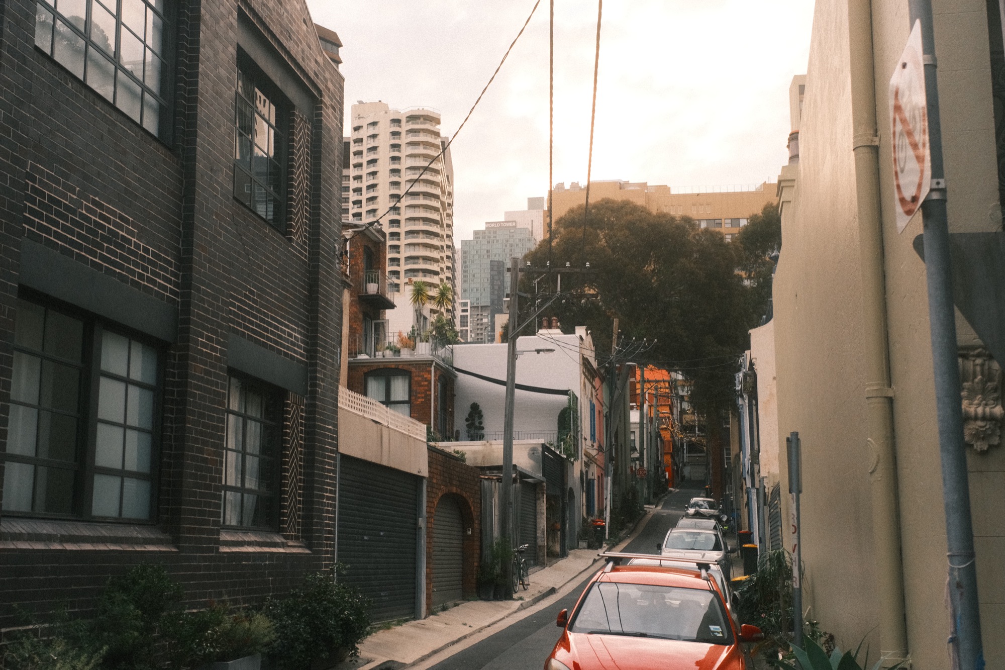 At the end of a narrow lane, apartment towers rise above the roofs.